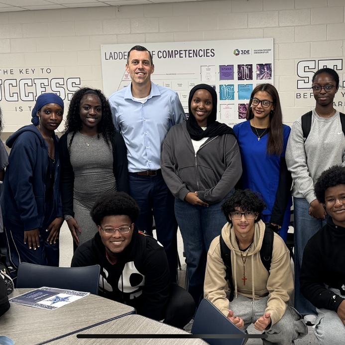 Andrew Sharos with a group of high school students in a classroom