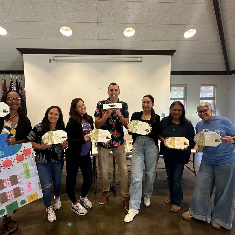 Andrew Sharos and a group of educators holding up cut-out projects from a workshop activity